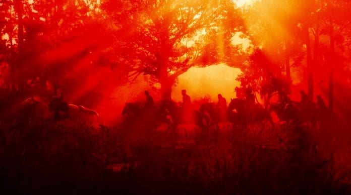 Red Dead Redemption 2 the protagonists ride horses through a sunset