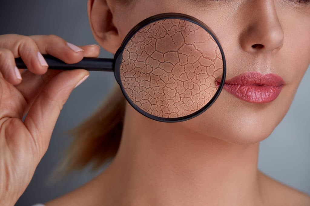 How Gamers Should Tackle Skincare 1 woman holding magnifier and showing damage to the skin, concept of rejuvenation and skincare