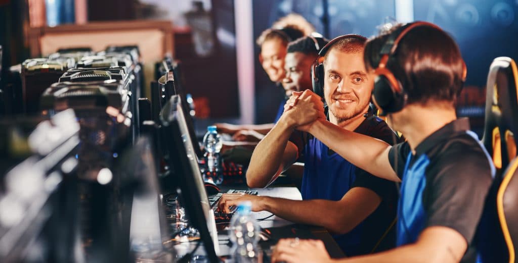 Why Lithuanians are enjoying esports more than ever 2 Professional cybersport team. Two happy male gamers shaking hands, celebrating success while participating in eSports tournament. Video games online competition