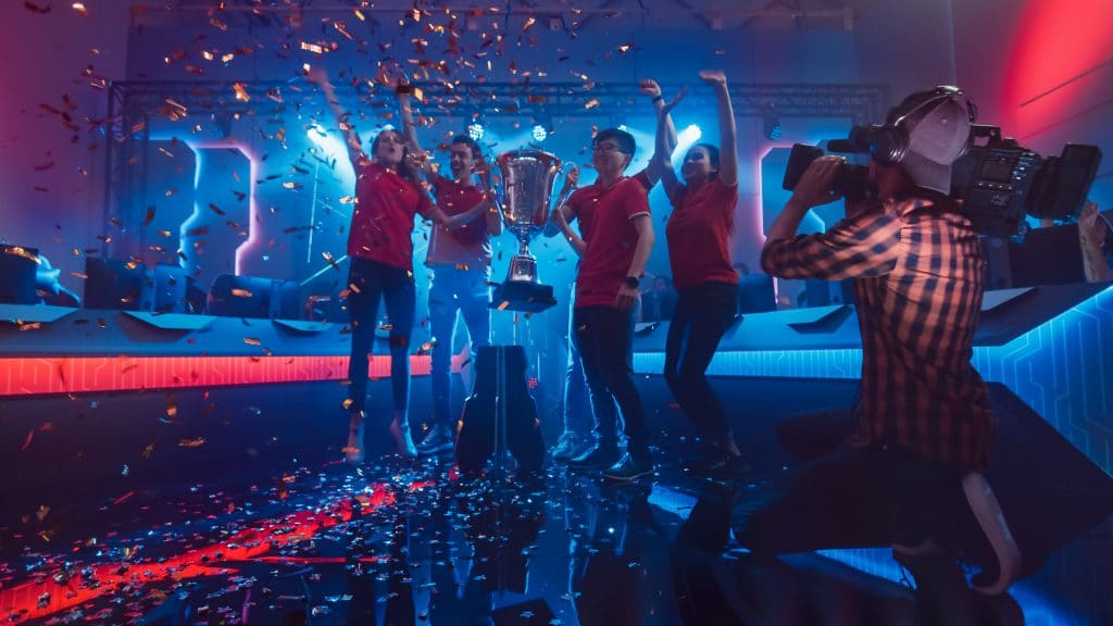 Tech Advancements Every Streamer Needs 2 Diverse Esport Team Winner of the Video Games Tournament Celebrates Victory Cheering and Holding Trophy in Big Championship Arena. Pro Computer Gaming Event with Player, Gamers Having Fun.