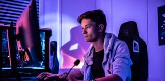 Writing A Video Game Walkthrough Article: 9 Ways To Make It Successfulย profile view of man sitting at desk bathed in purple light looking at computer screen