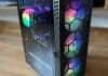 MONTECH X3 Mesh PC Case Review offset side view of MONTECH X3 Mesh pc case with rainbow lighted fans with a brown wood floor blurred background