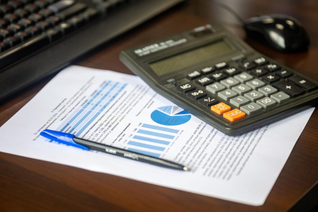A calculator and a pen resting on a printed financial report with charts