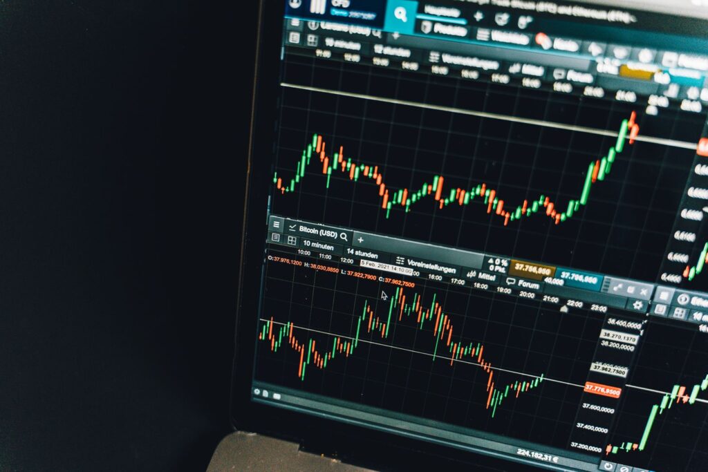 A laptop screen displaying a candlestick price chart for a cryptocurrency