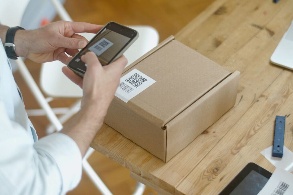 A person using a smartphone camera to scan a QR code label on a cardboard box
