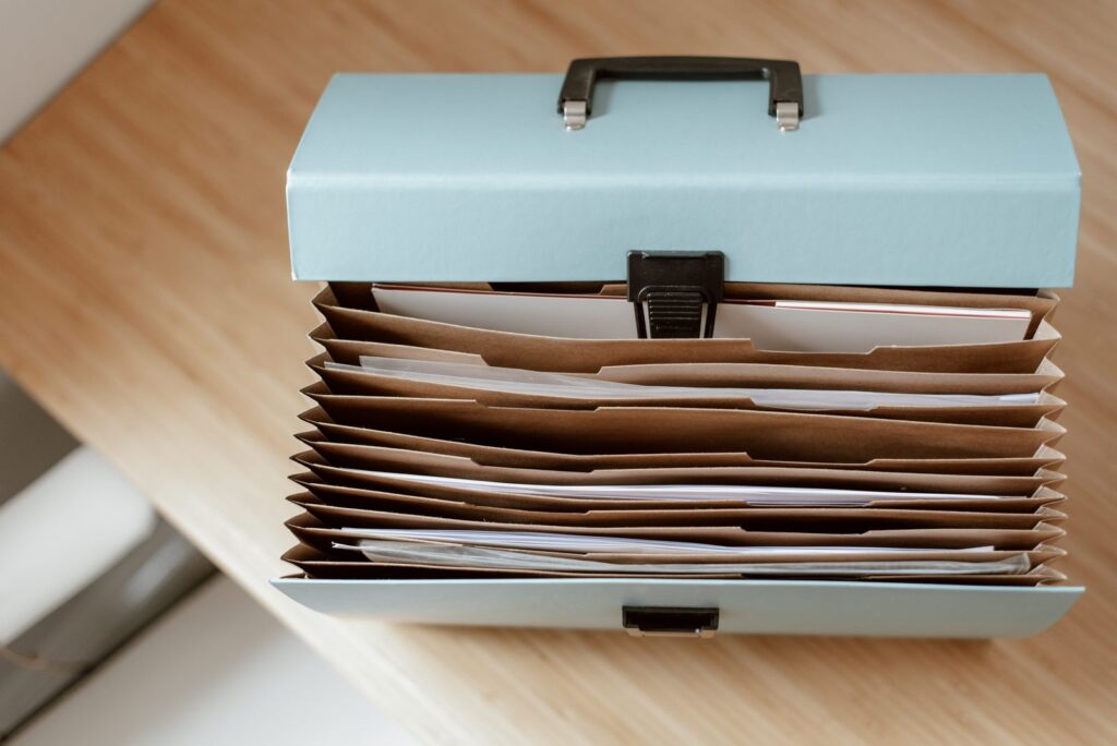 An open document box on a wooden desk filled with folders and papers