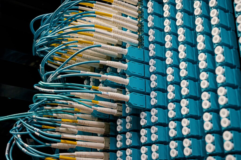 Rows of turquoise fibre optic patch cables plugged into a blue patch panel in a data centre