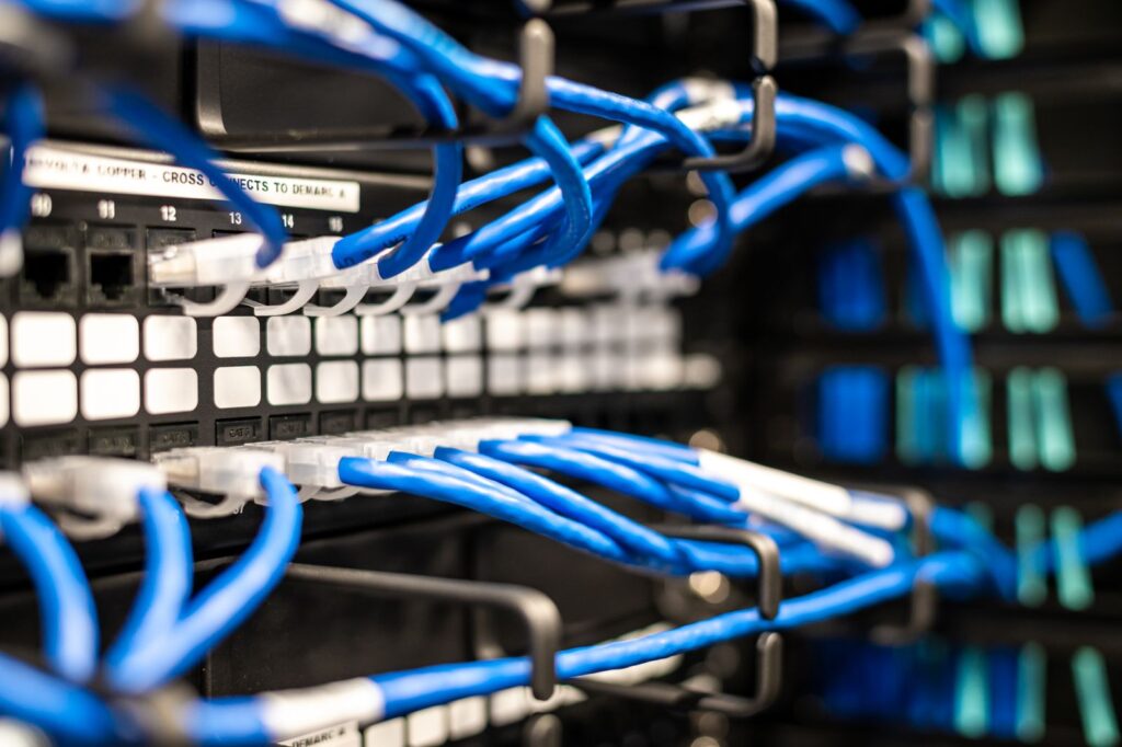 Blue network cables plugged into a patch panel in a server rack