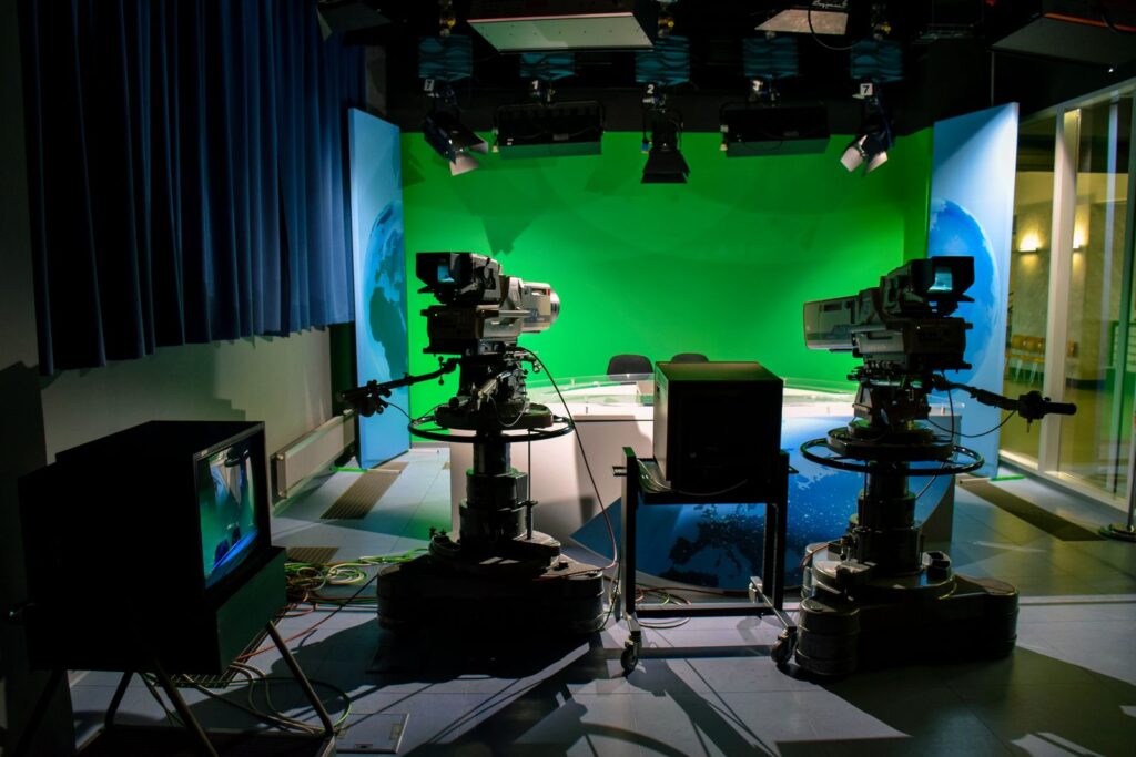 A television studio with two broadcast cameras facing a green screen set