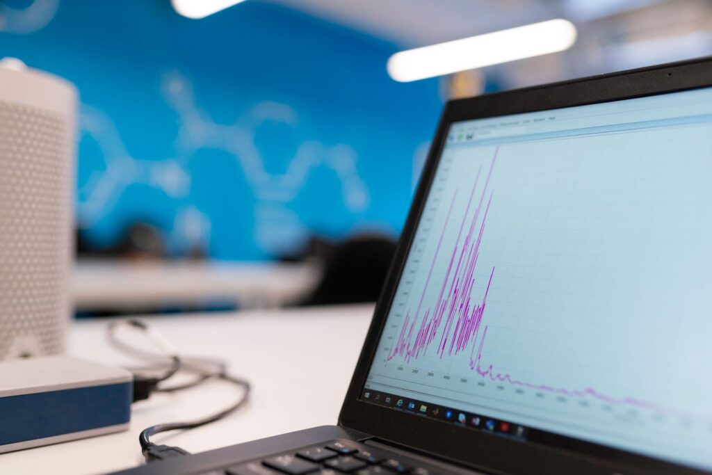 A laptop screen showing a spiky data graph in an office
