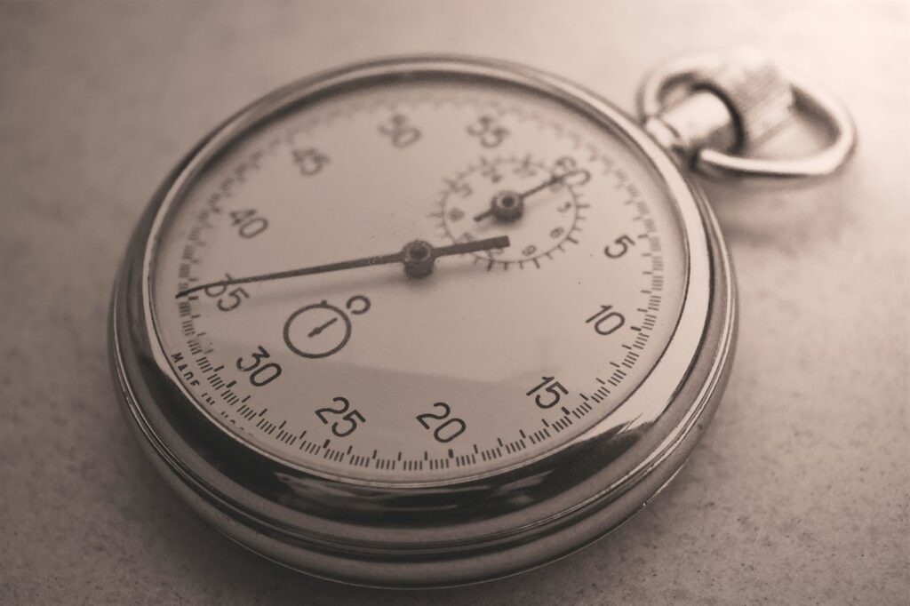 A close-up of a silver mechanical stopwatch in sepia tones